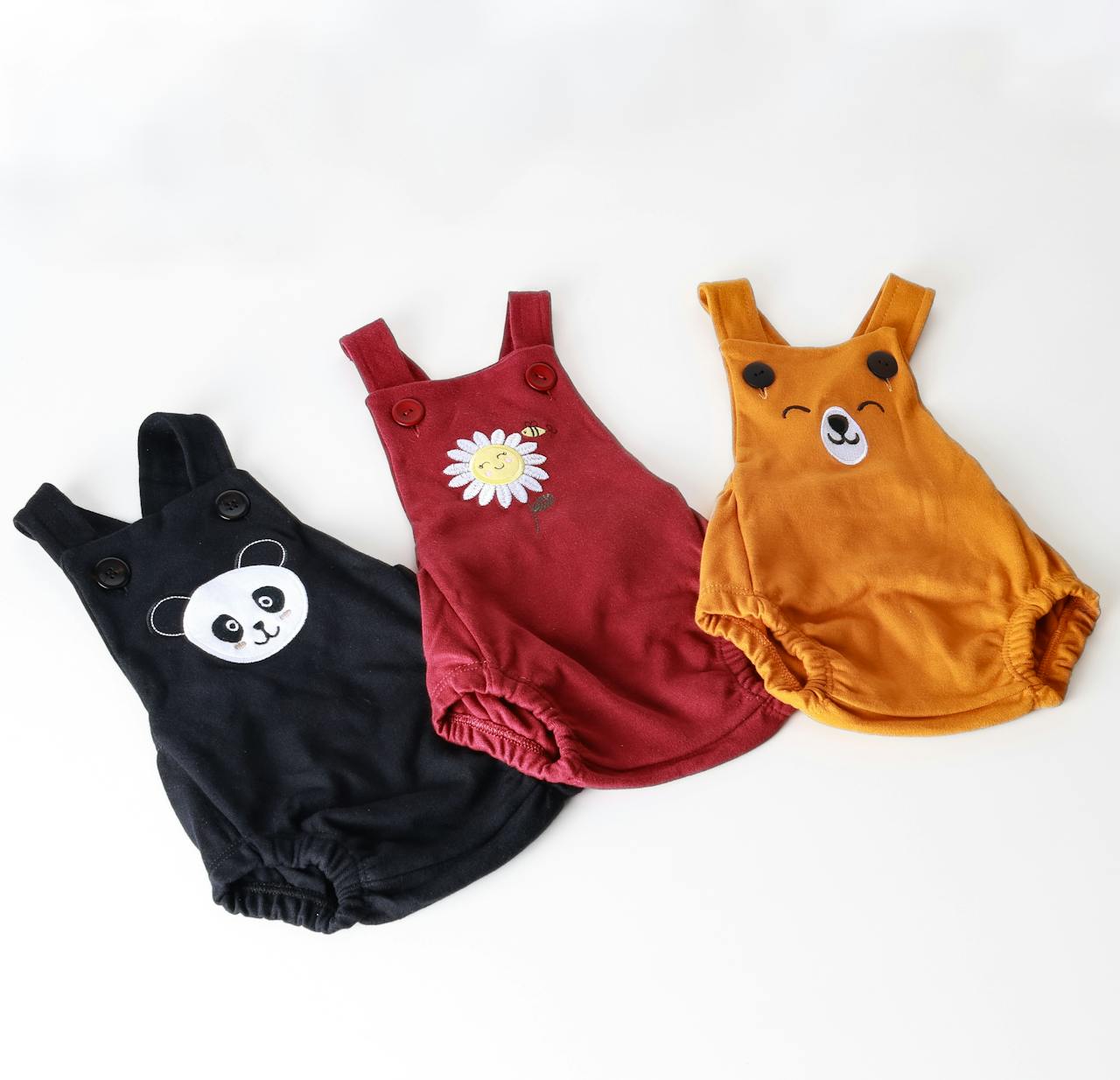 heros-img Set of three colorful baby onesies with adorable animal and flower designs on a white background.